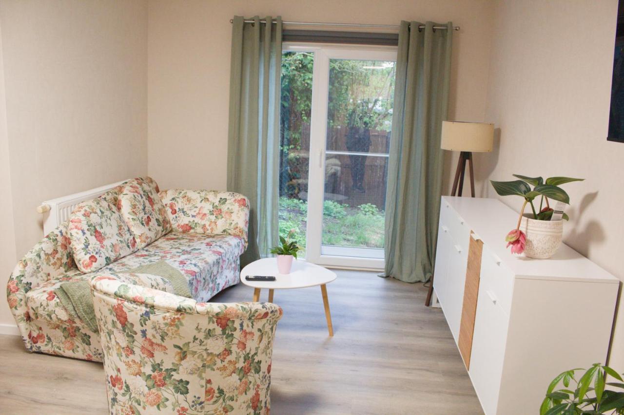 Wohnraum mit geblümtem Sofa, Sessel und Gartentür